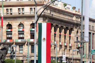 A large building with a flag on top of it. The flag is red, white, and green. Decoration to celebrate Independence Day in Mexico, zocalo