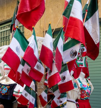 A display of Mexican flags hanging from a wall. The flags are red, white, and green. Decoration to celebrate Independence Day in Mexico, zocalo
