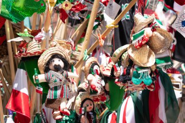 A display of Mexican dolls and hats. The dolls are dressed in traditional Mexican clothing and are hanging from a pole. Decoration to celebrate Independence Day in Mexico, zocalo