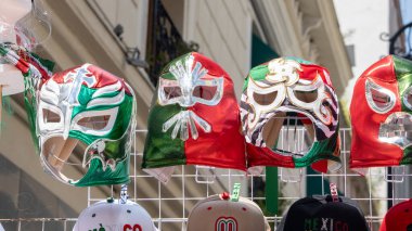 A row of colorful masks are displayed on a rack. The masks are of different colors and designs, and they seem to be for sale. Decoration to celebrate Independence Day in Mexico, zocalo