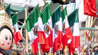 A group of flags with the word Mexico on them. The flags are hanging on a rack. The flags are red, white, and green. Decoration to celebrate Independence Day in Mexico, zocalo