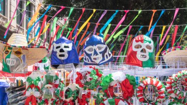 A display of Mexican masks and hats. The masks are blue, red, and green. The hats are also colorful. Decoration to celebrate Independence Day in Mexico, zocalo