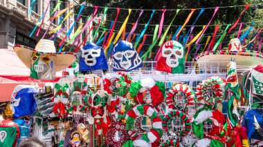A colorful display of Mexican masks and hats. The hats are decorated with skulls and bones. The display is set up in a market. Decoration to celebrate Independence Day in Mexico, zocalo