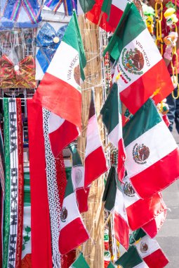 A bunch of flags hanging on a pole, including a Mexican flag. The flags are colorful. Decoration to celebrate Independence Day in Mexico, zocalo