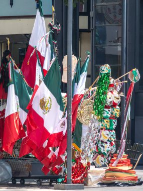 Flags of different colors and sizes are hanging on a pole. The flags are decorated with ribbons and other items. The scene is lively. Decoration to celebrate Independence Day in Mexico, zocalo