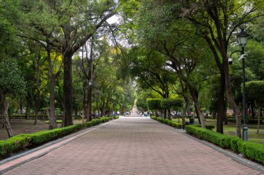 A long, brick walkway with trees on either side. Historic center of Queretaro City, decorations and traditions to celebrate Mexico's Independence Day, colonial architecture, alleys and facades