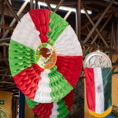 A large Mexican flag is hanging from the ceiling. A smaller flag is hanging next to it. Historic center of Queretaro City, decorations and traditions to celebrate Mexico's Independence Day, colonial architecture, alleys and facades