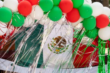 A bunch of balloons with a Mexican flag in the middle. The flag is red, white, and green. Historic center of Queretaro City, decorations and traditions to celebrate Mexico's Independence Day, colonial architecture, alleys and facades