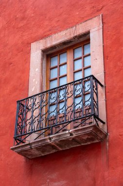 Ahşap çerçeveli ve metal parmaklıklı bir pencere. Korkuluklar süslenmiş ve pencere açık. Queretaro şehrinin tarihi merkezi, Meksika 'nın Bağımsızlık Günü' nü, sömürge mimarisini, sokaklarını ve cephelerini kutlamak için dekorasyon ve gelenekler