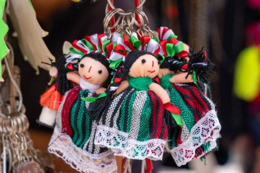 A collection of dolls with colorful clothing and accessories. The dolls are arranged in a row. Historic center of Queretaro City, decorations and traditions to celebrate Mexico's Independence Day, colonial architecture, alleys and facades