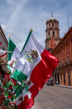 Flags of Mexico are displayed on a street. The flags are red, white, and green. Historic center of Queretaro City, decorations and traditions to celebrate Mexico's Independence Day, colonial architecture, alleys and facades