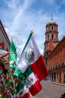 Flags of Mexico are displayed on a street. The flags are green, white, and red. Historic center of Queretaro City, decorations and traditions to celebrate Mexico's Independence Day, colonial architecture, alleys and facades