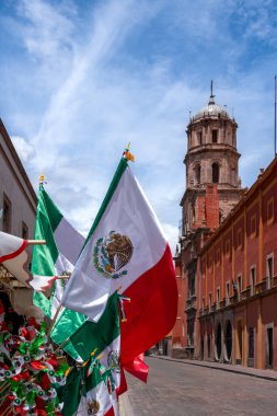 Flags of Mexico are displayed on a street. The flags are red, white, and green. Historic center of Queretaro City, decorations and traditions to celebrate Mexico's Independence Day, colonial architecture, alleys and facades