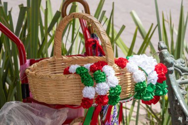 Renkli kurdele ve çiçeklerle dolu bir hasır sepet kırmızı bir arabada duruyor. Queretaro şehrinin tarihi merkezi, Meksika 'nın Bağımsızlık Günü' nü, sömürge mimarisini, sokaklarını ve cephelerini kutlamak için dekorasyon ve gelenekler