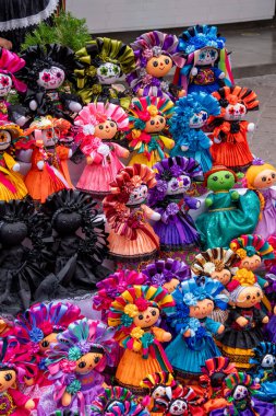 A colorful display of dolls with flowers and skulls. The dolls are arranged in a pyramid shape. Historic center of Queretaro City, decorations and traditions to celebrate Mexico's Independence Day, colonial architecture, alleys and facades