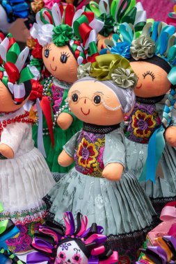 A group of dolls with colorful clothing and accessories. The dolls are arranged in a row. Historic center of Queretaro City, decorations and traditions to celebrate Mexico's Independence Day, colonial architecture, alleys and facades
