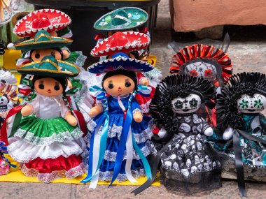 A display of various Mexican dolls, each with unique clothing and accessories. Historic center of Queretaro City, decorations and traditions to celebrate Mexico's Independence Day, colonial architecture, alleys and facades