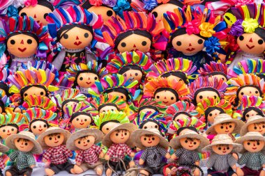 A collection of colorful dolls with hats and flowers. The dolls are arranged in rows. Historic center of Queretaro City, decorations and traditions to celebrate Mexico's Independence Day, colonial architecture, alleys and facades