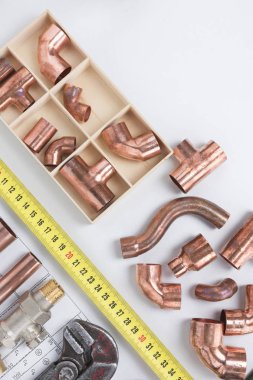 Bakır boru dirsek eklem, mezura ve sıhhi tesisat araçları düz beyaz arka plan üzerinde yatıyordu