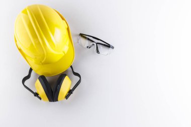 Construction safety equipment including hard hat, earmuffs, and protective goggles on white background with copy space clipart