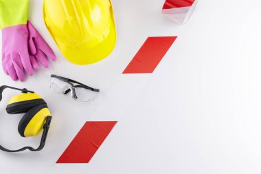 Kırmızı ve beyaz bariyer bandın bir çift eldiven, kulaklıklar, lastik eldiven ve baret beyaz arka plan üzerinde kopya uzaydan içerir inşaat Emanet dişli şerit