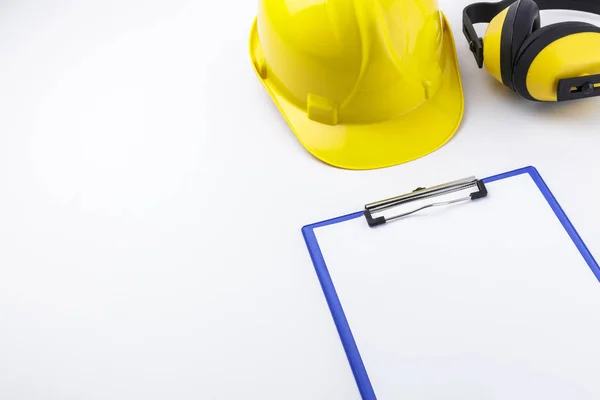 Hard hat, earmuffs, and clipboard on a white background with copy space