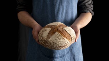 Sourdought çavdar ekmeği siyah bir arka plan üzerinde tutan eller