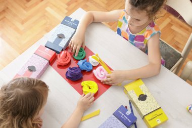 Çocuklar masada renkli modelleme kil ile oynuyor