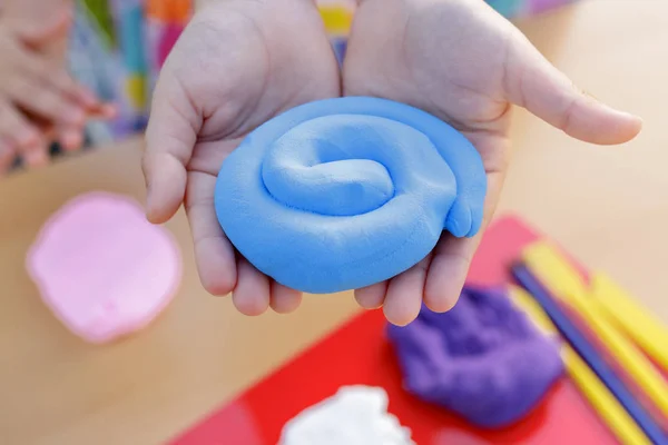Hands holding a lump of blue modeling soft clay