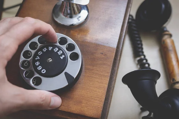 Hand dialing on an antique wooden rotary telephone