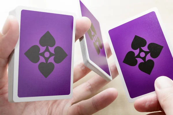 Hands with deck of playing cards showing purple back design
