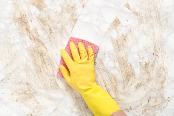 Mão vestindo luva limpando contador de mármore sujo com esponja — Fotografia de Stock