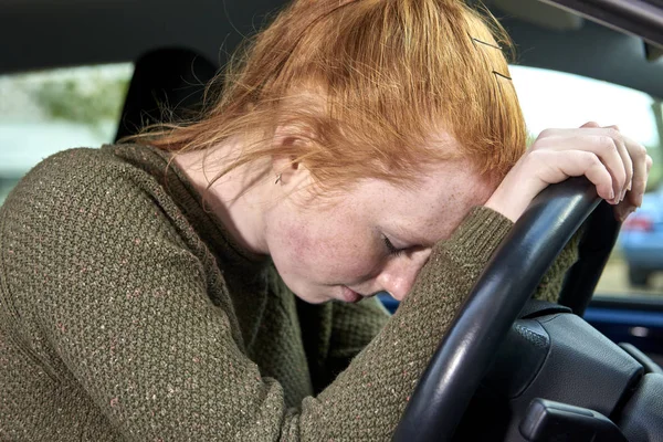 Mujer joven cansada con la cabeza contra el volante — Foto de Stock