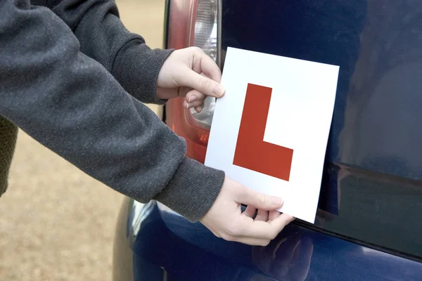 Sticking a Learner Driver 'L' Sign at the Rear of a Car Stock Photo