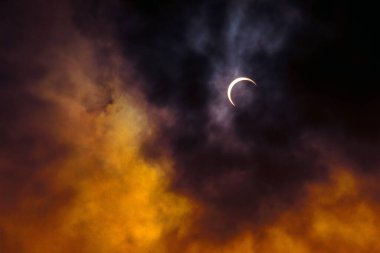 Partial annular solar eclipse, known in such circumstances as a ring of fire, seen in Malaysia in 26th Dec 2019. Cloudy weather in the Kuala Lumpur obscuring much of the view. Dramatic colour applied. clipart