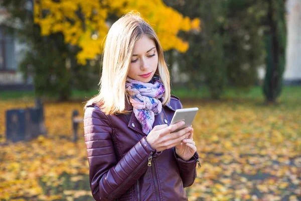 Happy teen girl with phone smile during walking on autumn park. Fall concept — Stock Photo, Image