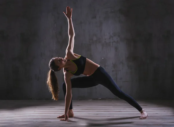 Фитнес-женщина тренируется в темной студии. Молодая девушка позирует на черном фоне — стоковое фото