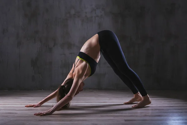 Фитнес-женщина тренируется в темной студии. Молодая девушка позирует на черном фоне — стоковое фото