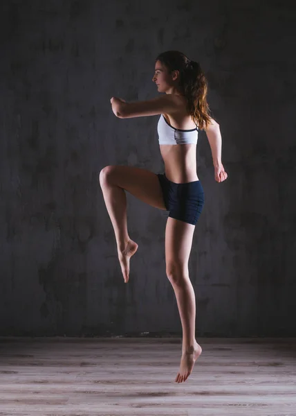 Fitness woman training in dark studio. Young girl posing on black background — Stock Photo, Image