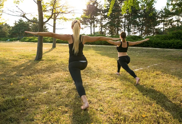 Mulheres do esporte fazendo ioga lá fora de manhã. Fitness meninas relaxar no parque — Fotografia de Stock