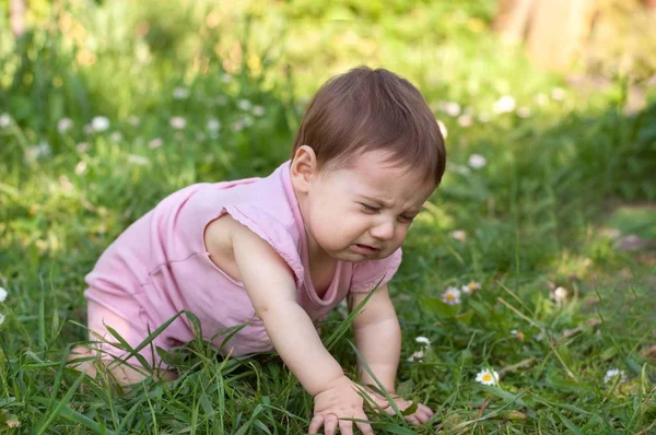 Bebê está sentado na grama e chorando . — Fotografia de Stock