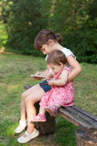 Meninas bonitos estão jogando jogos no telefone celular . — Fotografia de Stock