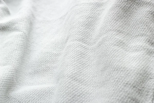 Crumpled white textile with folded for background. Top view material texture. Close-up minimalistic concept.