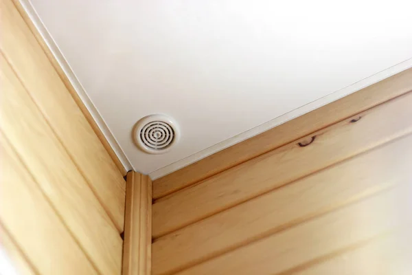 Fire alarm of fire detector on a ceiling. Smoke sensor in corner of room, wall of wood. Fire safety system