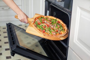 Close. Kadın el fırında pizza koymak.