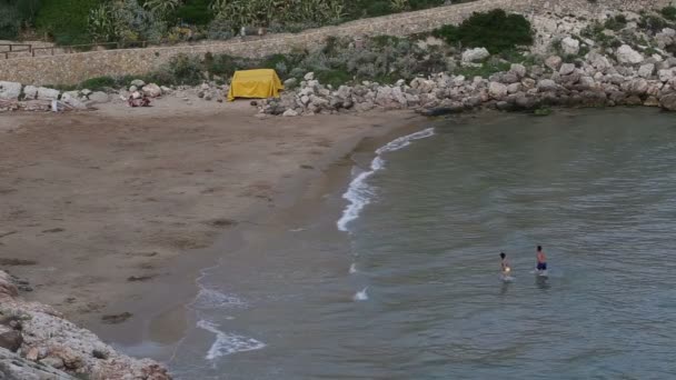 Пара купается в море на диком пляже — стоковое видео