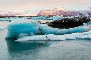 Gün doğumunda, İzlanda 'da Vatnajokull buzulunun yakınındaki Jokulsarlon gölünde buzdağları