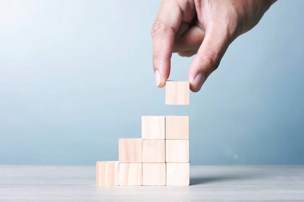 Wood Block Cubic stack with Hand on table Blue Tone Background. Free Copy Space.