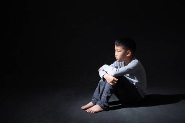 Asya 'lı Çocuk Kara Arkaplan' da dizlerinin üstüne çöküp oturuyor. Konsept: depresyonda. Hayal kırıklığına uğradım. Duygu. 