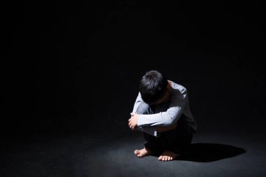Asya 'lı Çocuk Kara Arkaplan' da dizlerinin üstüne çöküp oturuyor. Konsept: depresyonda. Hayal kırıklığına uğradım. Duygu. 